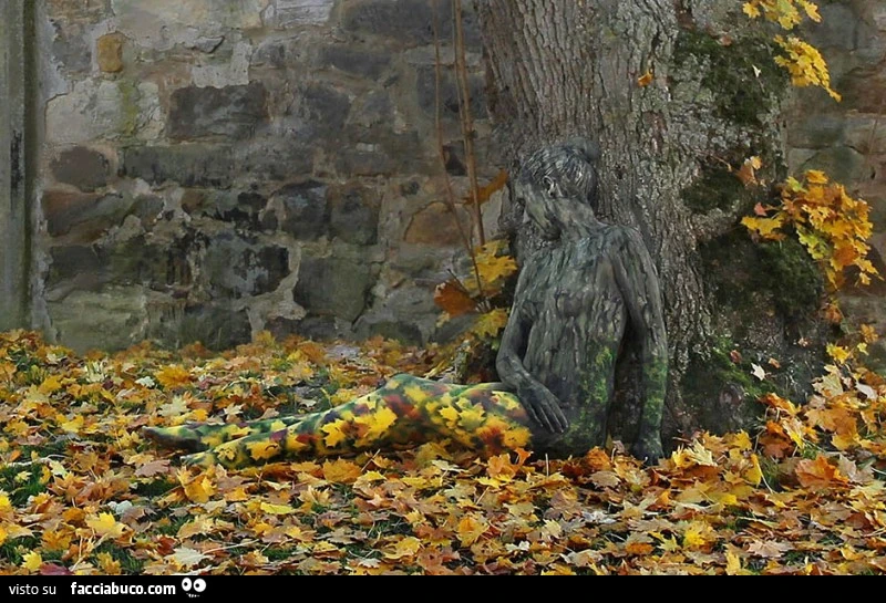 Donna mimetizzata accanto all'albero