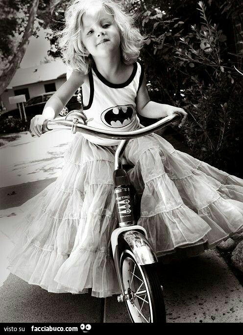 Bambina in bicicletta con maglietta di Batman